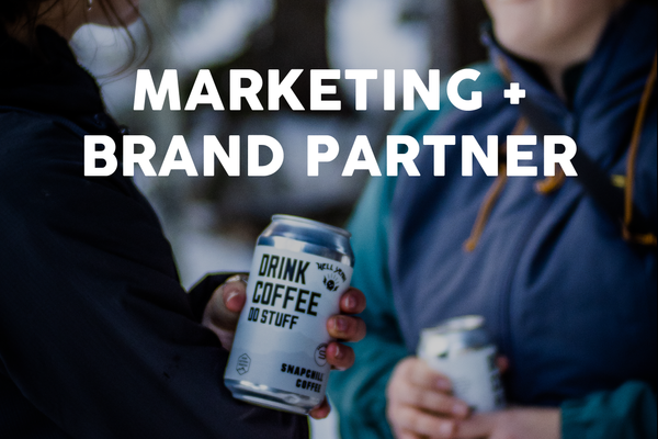 Marketing + Brand Partner text overlaid on top of hands holding cold brew cans