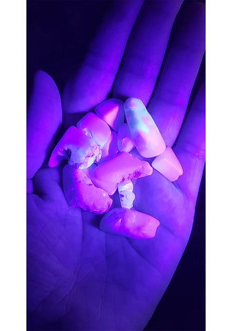 Image of hand under UV light, showing off fluorescent opal.