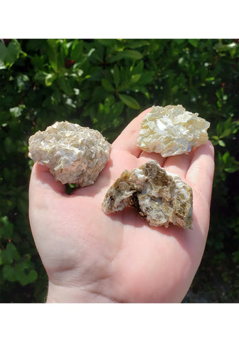 Hand holding three large gold mica clusters