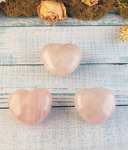 Three puffy rose quartz heart carvings on display