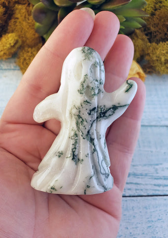 Hand holding a tree agate ghost carving