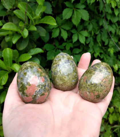 Hand holding three unakite carved eggs