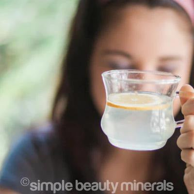woman holding hot drink with lemon slice | hydration for winter skin | simple beauty minerals