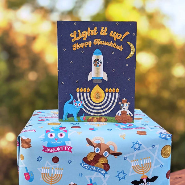 Whimsical Hanukkah animals greeting card on top of gift wrapped in Hanukkah Friends wrapping paper