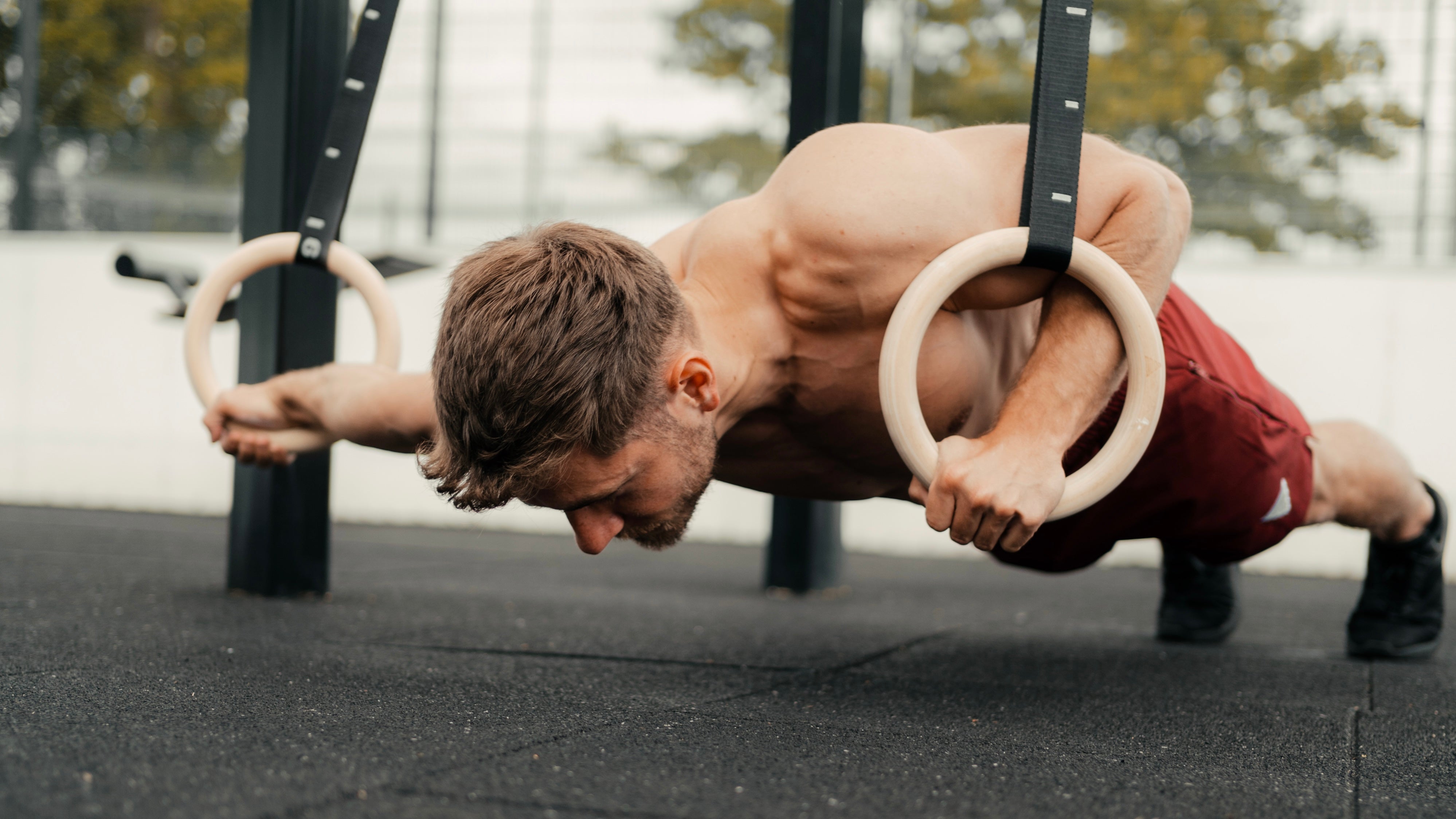 calisthenics athlete performing strength exercise on workout rings by gornation