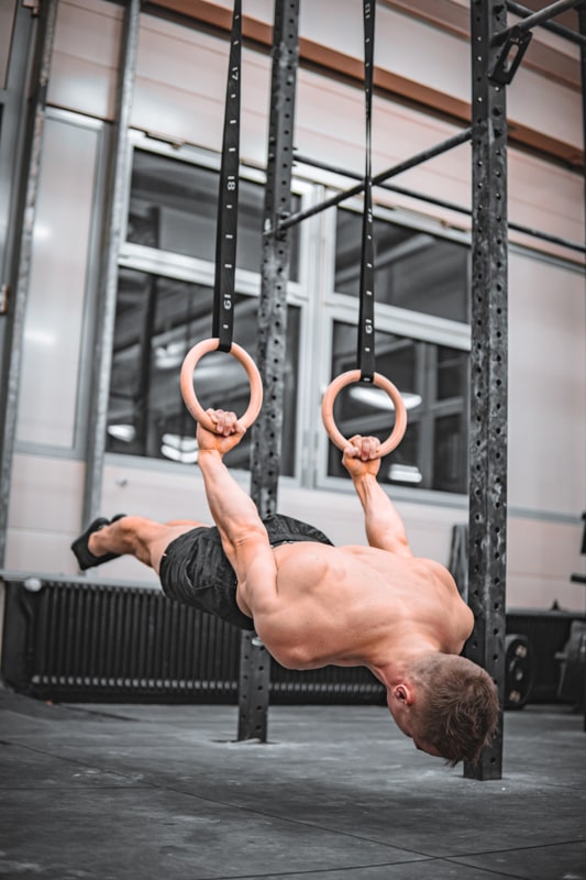 athlete is holding a back lever on rings