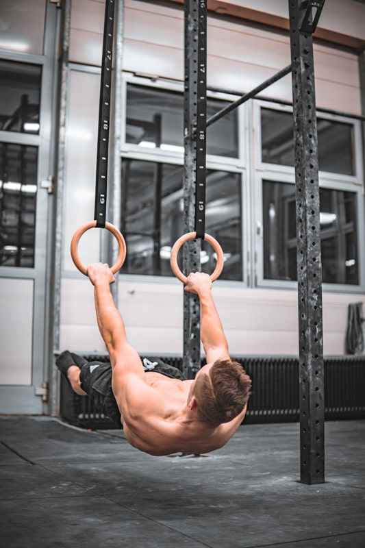 athlete is holding a front lever on rings in a gym