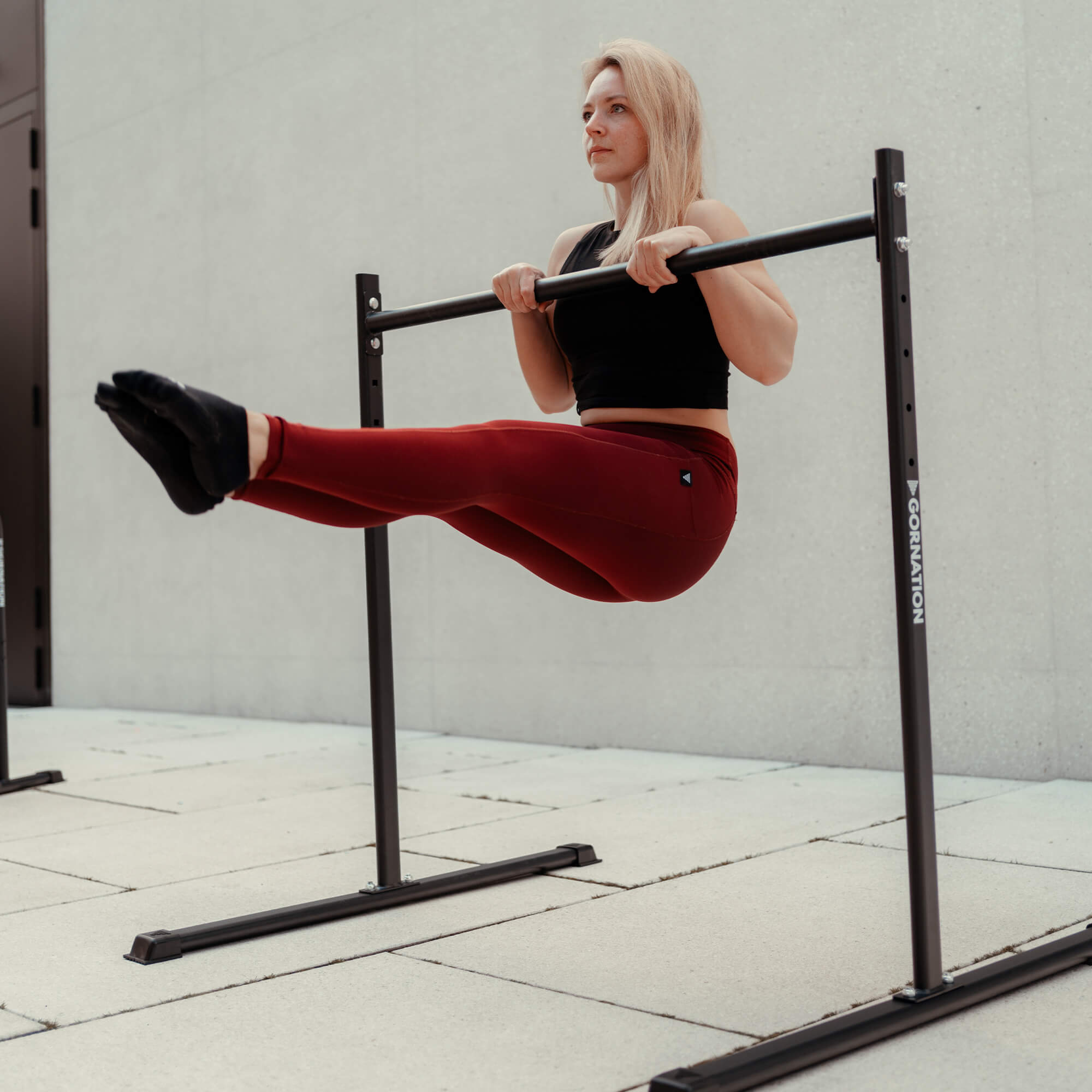 female calisthenics athlete doing l-sit pull ups on gornation static bar