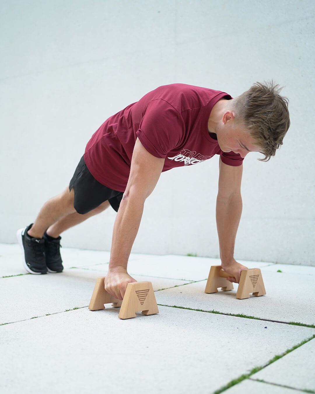 athlete in planche lean position on wooden parallettes by gornation
