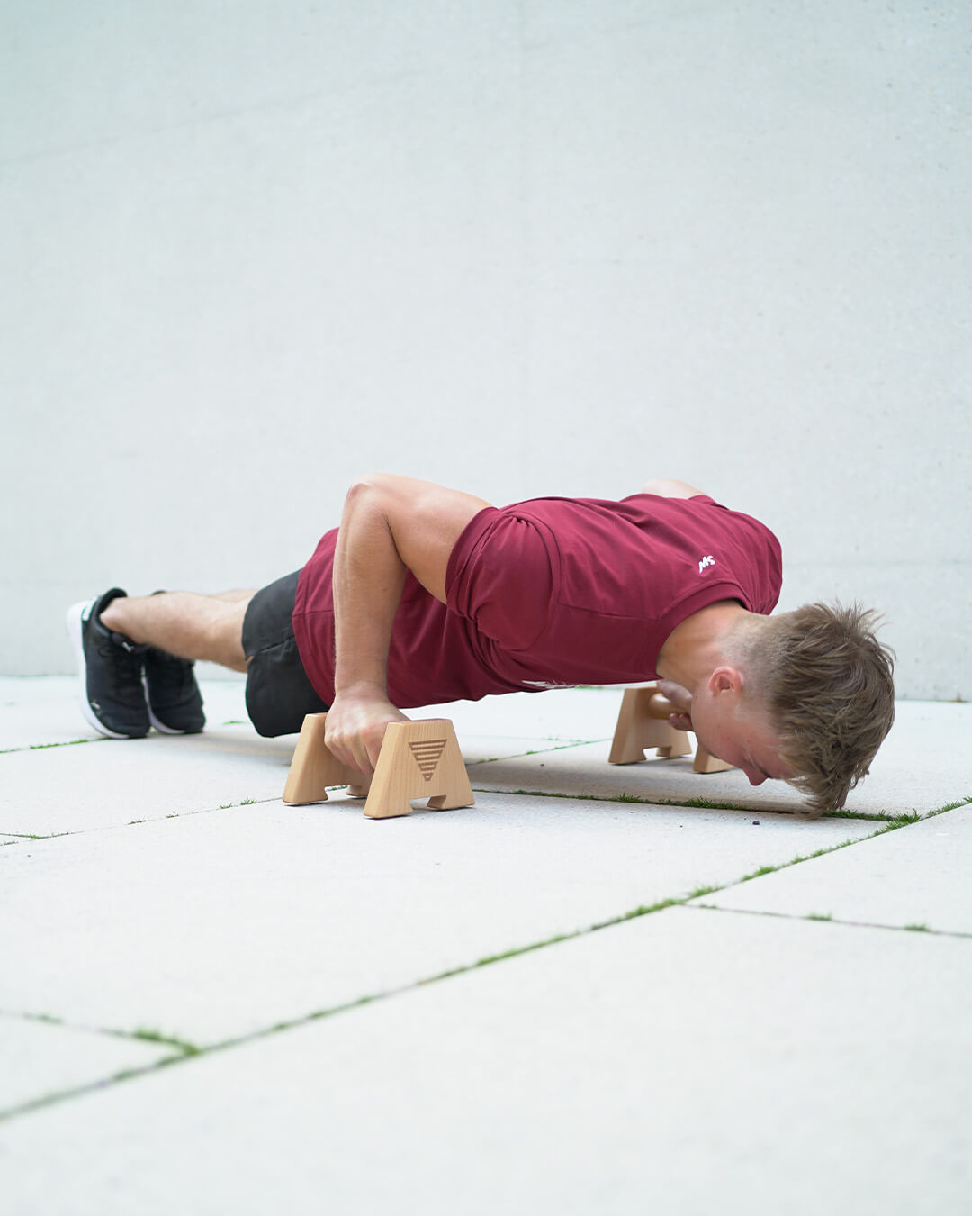 calisthenics athelte doing push ups on wooden parallettes by gornation