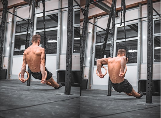 calisthenics athlete does dips on rings in a gym