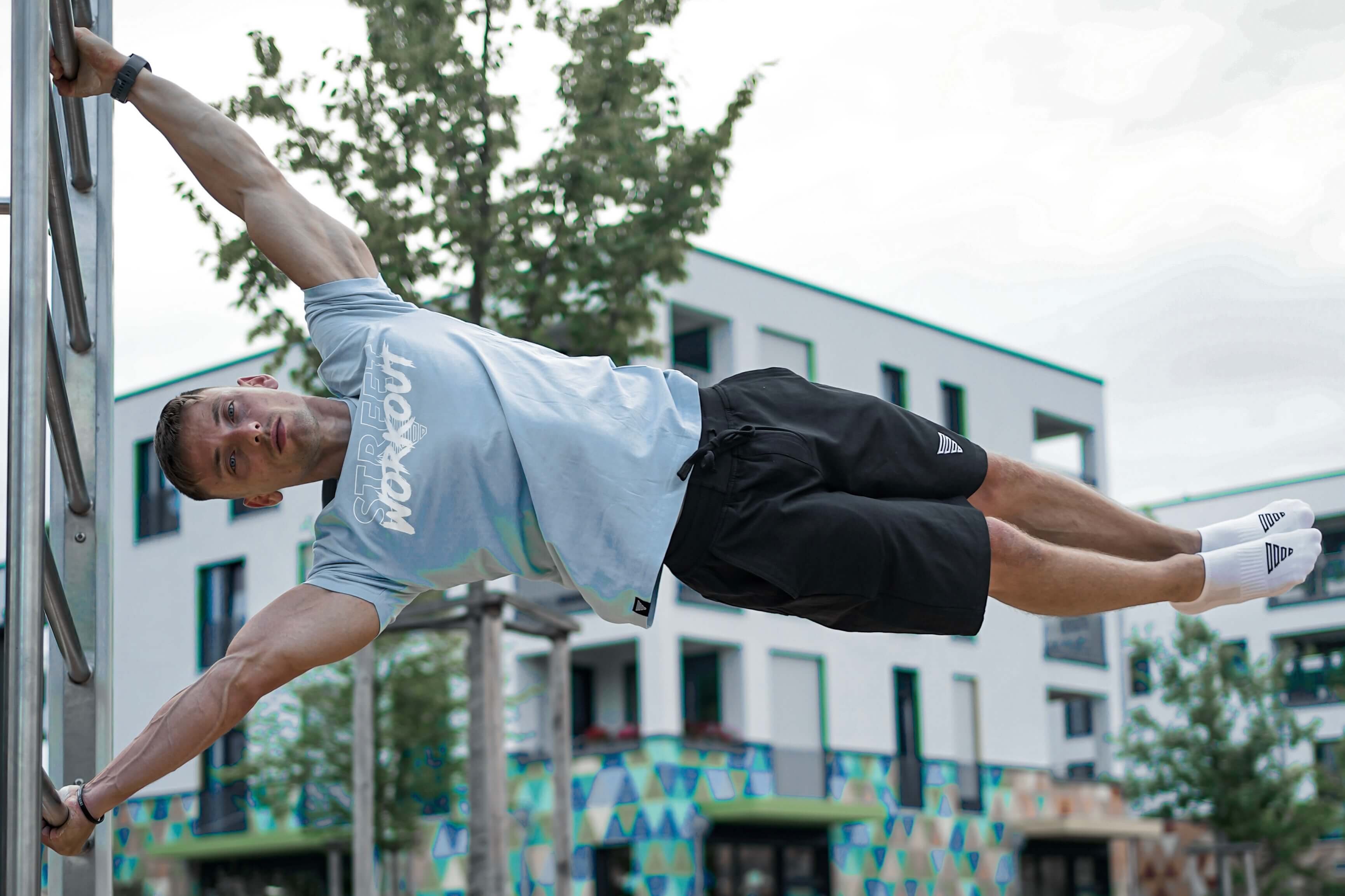 Calisthenics Athlete performing a Human Flag while wearing a Street Workout Shirt and Shorts by GORNATION