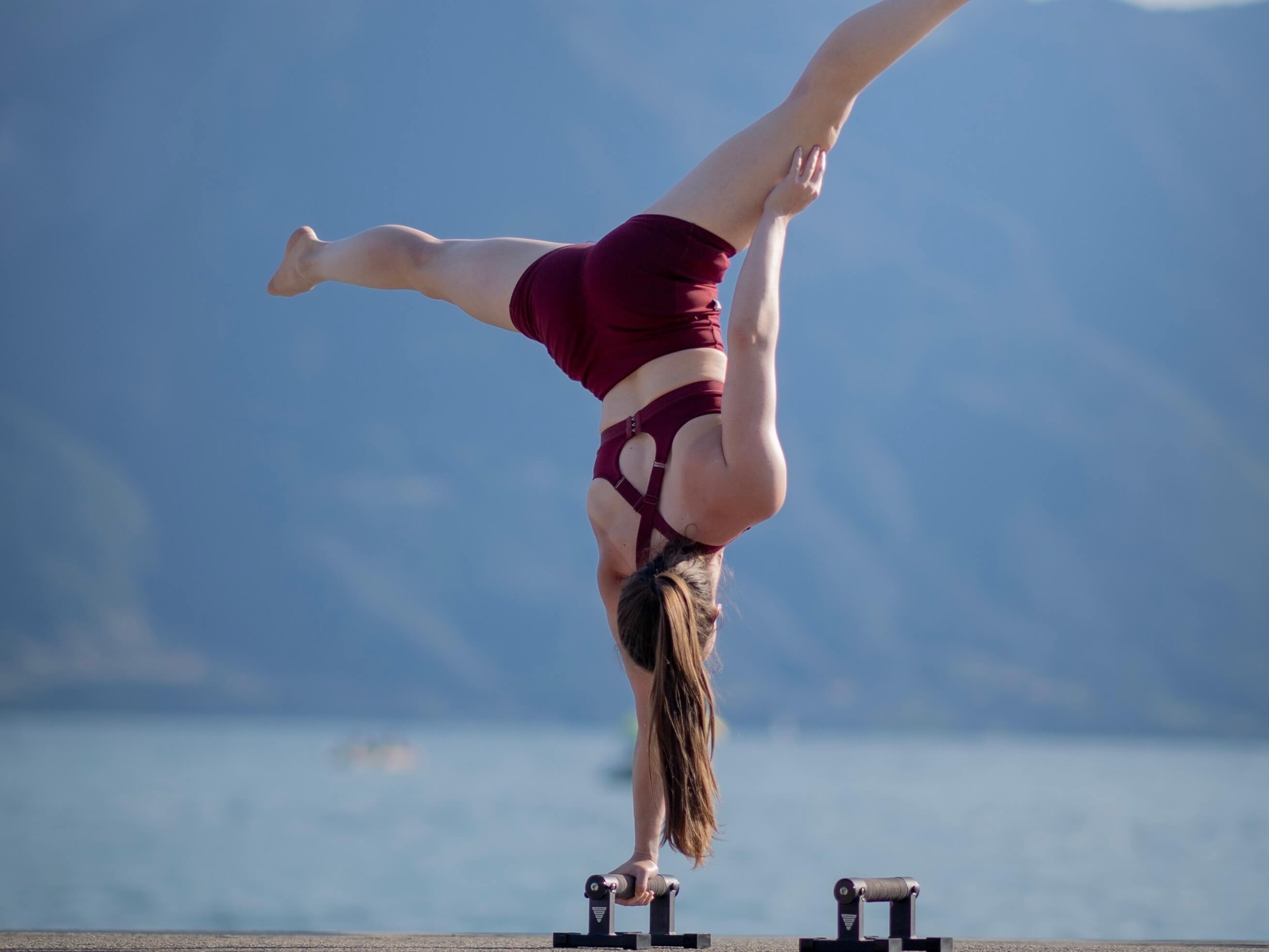 strong swiss calisthenics female athlete is doing a one arm handstand