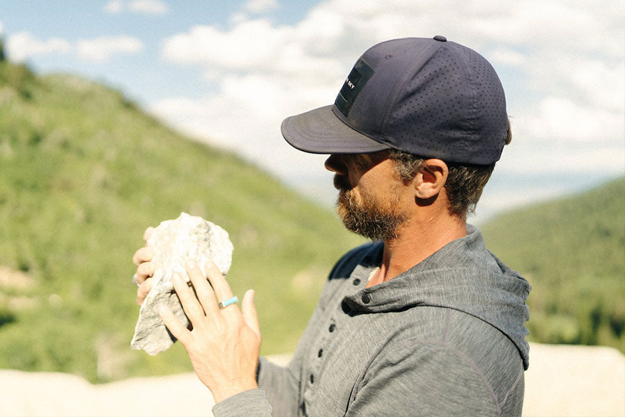 man inspecting the quality of a stone found in nature wearing walter sky