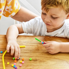 Little boy threading beads