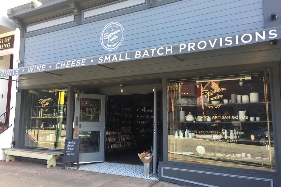 Exterior of The Epicurean Trader store with signage reading “Wine, Cheese, Small Batch Provisions” for Mother's Day shopping.