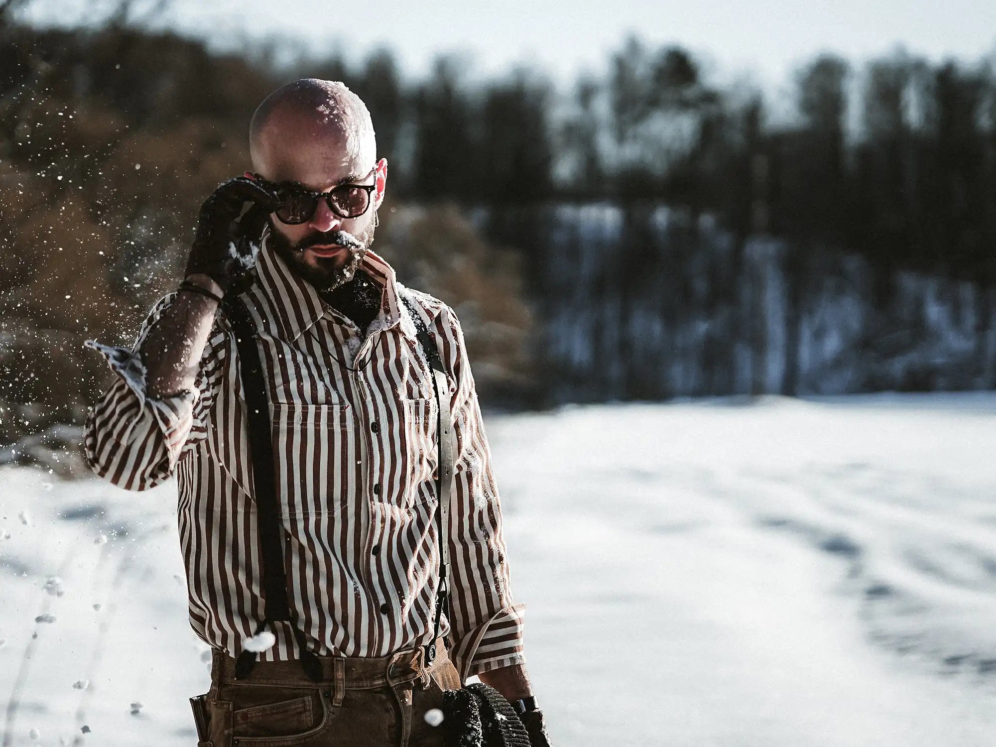 Man in snowy forest wearing sunglasses and leather wiseguy original suspenders