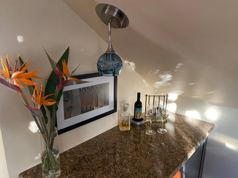 the 763 swell globe on a slanted ceiling above a home bar with birds of paradise flowers in a vase
