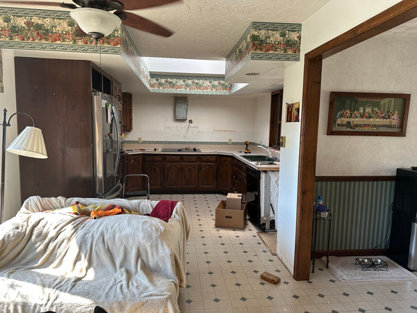 photo of dated 1980s kitchen within a remodel, sheets on furniture and empty cupboards