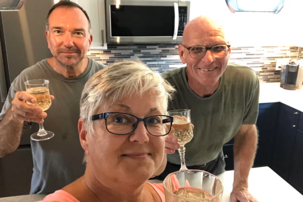 photo of homeowners and contractor toasting to a finished kitchen remodel with wine glasses