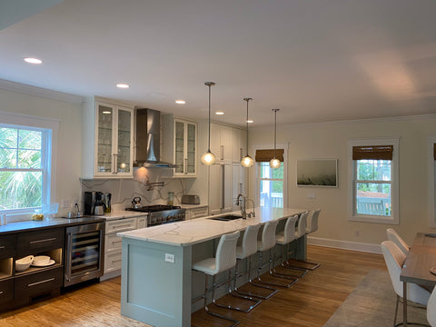 Bicycle Glass Arctic Swell 767 Single Pendant Lights in Gray with Brushed Nickel Hardware and Downrods, wide shot of white marble kitchen island featuring a sink and six white leather barstools 