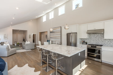 Bicycle Glass Pendant Lighting Alloy 768 in clear with single pendant hardware kits in brushed nickel, hang straights and cord lengthening over a modern white kitchen island, lights on, wide shot of vaulted ceiling and living room 