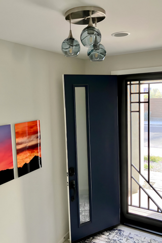 picture of front entry of house with a 3 glass globe chandelier on ceiling and door open