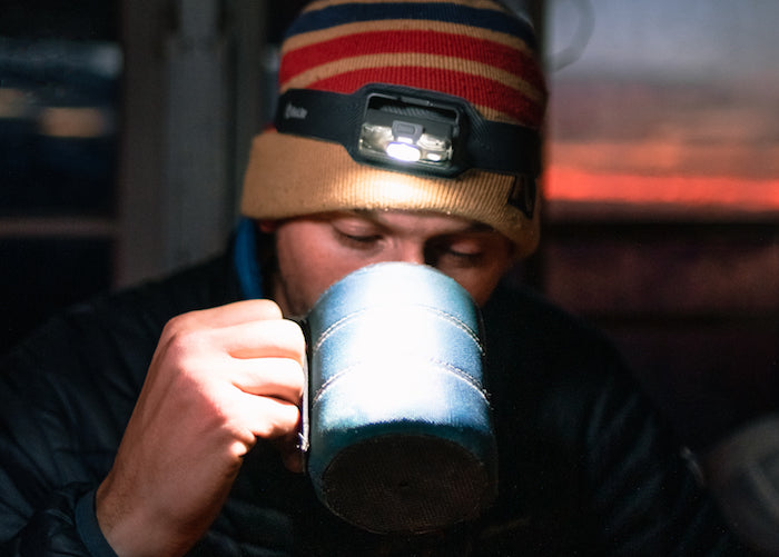 Man drinking coffee at sunrise with BioLite Headlamp