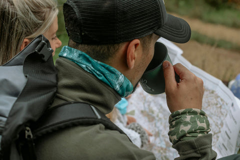 Man reading map whilst drinking coffee and wearing a Ruffnek scarf and wristband