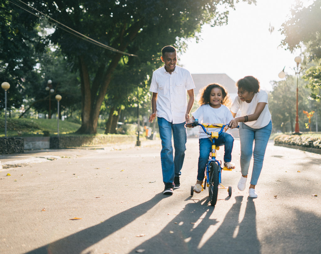 Parents helping happy child ride a bike