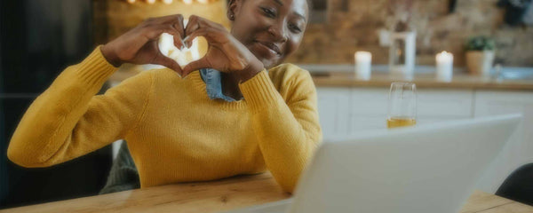 Black woman making heart shape with hands during video conference