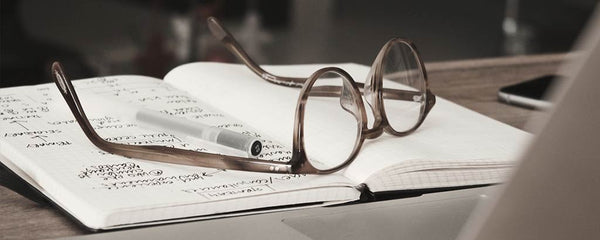 Glasses on notebook in front of laptop