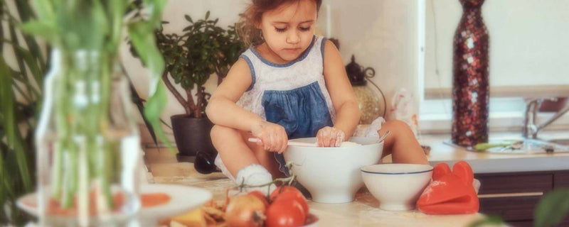 Young girl preparing food while sitting on kitchen counter