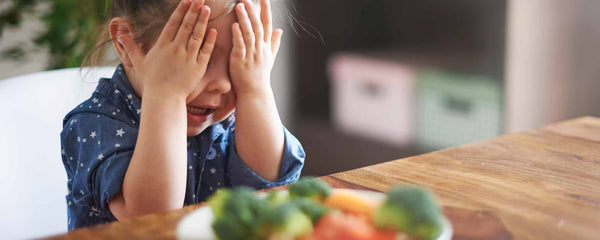 Young girl unhappy with a plate of vegetables