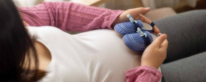 Pregnant woman with baby slippers on belly