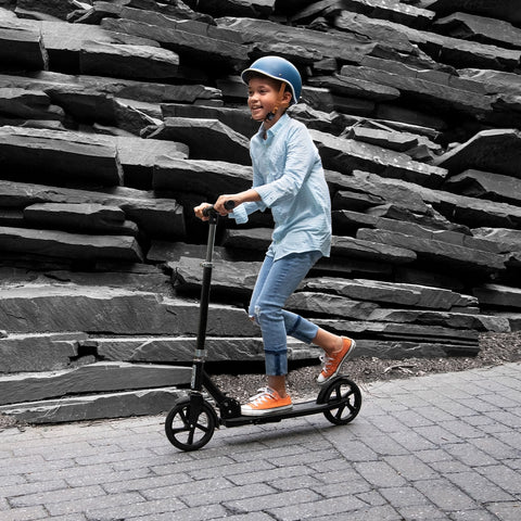 boy in a helmet riding a two wheel kick scooter