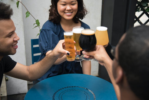 A group of friends hold glasses of beer in a "cheers."