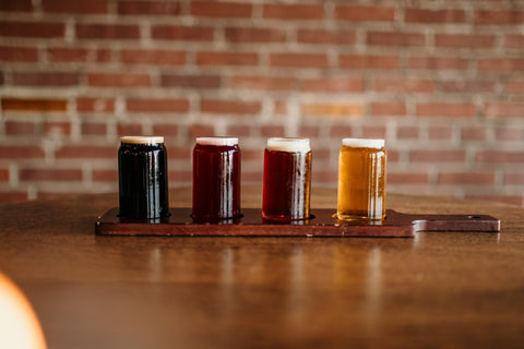 A flight of various beer samples sitting on a table.