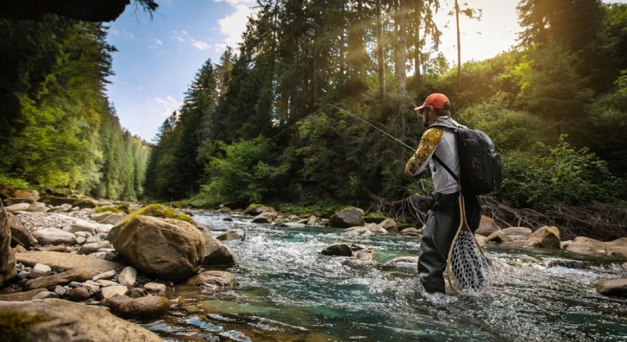 Angler with backpack in a river