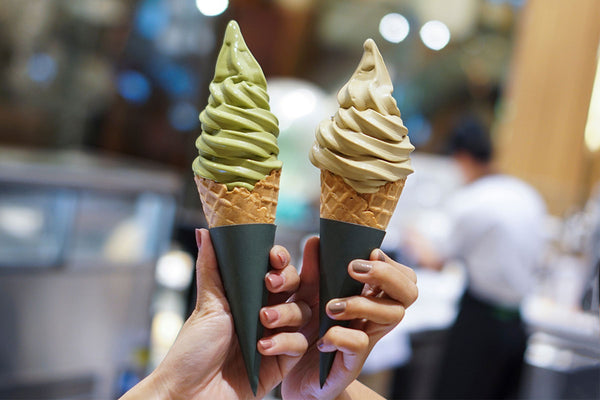 Female friends hold up soft serve ice cream cones.