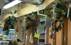 Hairy boar heads with sausages hanging from their tusks