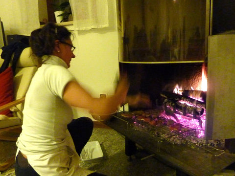 Birgitta cooks bread and sweet lamb cutlets on a wood fire.