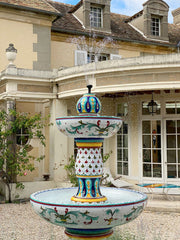 Lava stone ceramic fountain in front of a grand house.