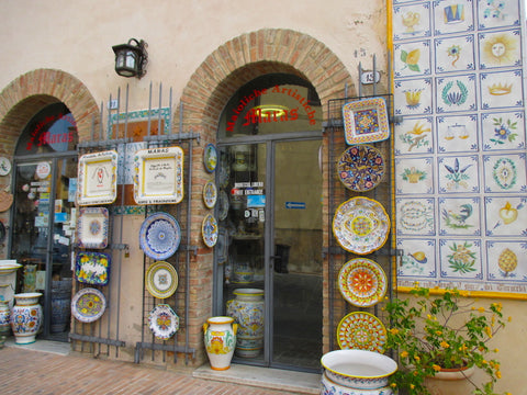 Shops lining the main street of the old town of Deruta display their wares on the walls outside.