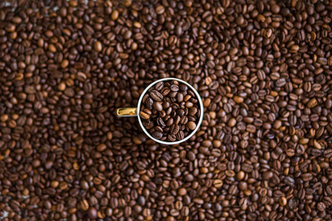 coffee beans around a coffee mug