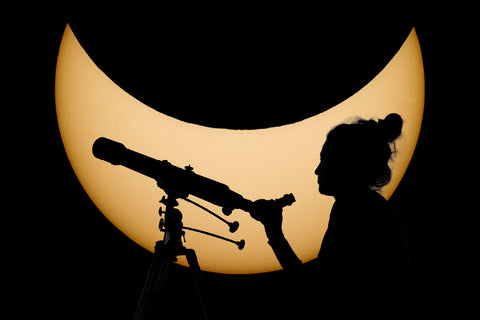 shilouette of a woman looking through a telescope