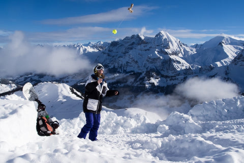 a man on top of a snowy mountain playing kendama