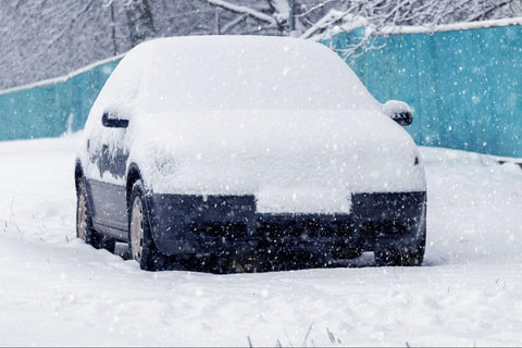 snow-covered car stranded roadside during snowfall