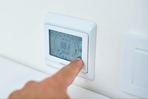 person adjusting thermostat in home