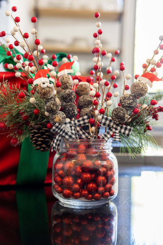 Christmas themed mason jar centerpiece with Frooze Balls poked on a stick coming out of the jar 